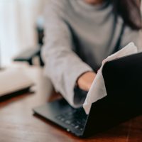 A working woman wipe the laptop clean in home office.Work from home and covid19 concept. A working woman wipe the laptop clean in home office.Work from home and covid19 concept.