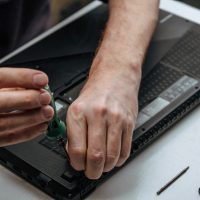 computer technician installs the main part of the bottom cover of laptop after repair and maintenanc computer technician installs the main part of the bottom cover of laptop after repair and maintenanc