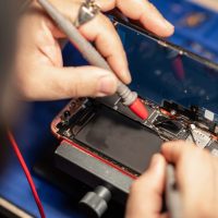Expert performs smartphone battery repair with precision tools at a tech workshop Expert performs smartphone battery repair with precision tools at a tech workshop