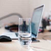 Glass of water on desk near laptop Glass of water on desk near laptop