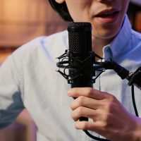 Male vlogger using microhpone to record podcast episode Male vlogger using microhpone to record podcast episode