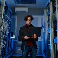 Man IT specialist with laptop working on datacenter software update Man IT specialist with laptop working on datacenter software update