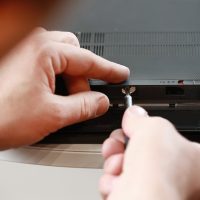 Repairman’s hands unscrewing the screws from the laptop case with a screwdriver. Computer service Repairman's hands unscrewing the screws from the laptop case with a screwdriver. Computer service
