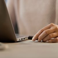 Woman plugging a USB flash drive into her laptop Woman plugging a USB flash drive into her laptop
